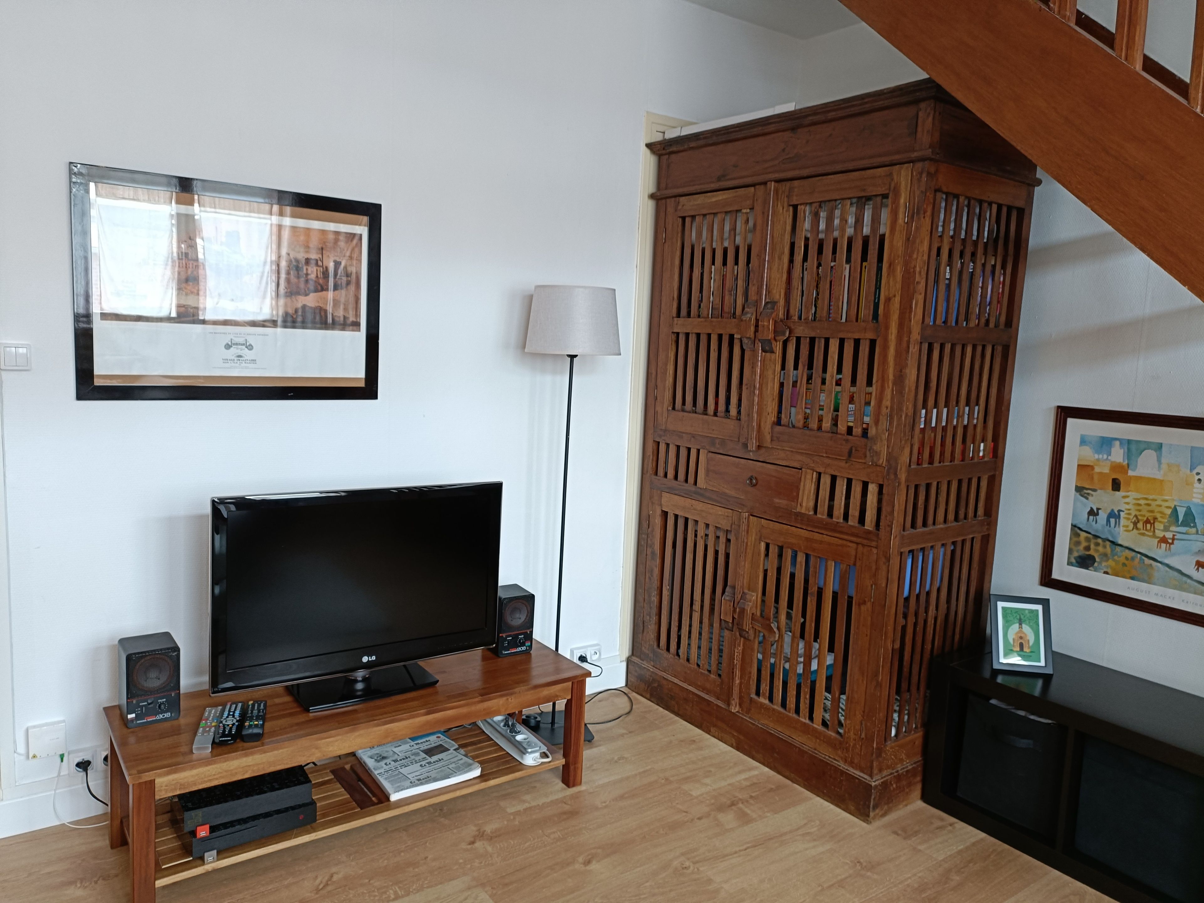 Een woonkamer met een flatscreen televisie, een houten salontafel en een groot houten kast.
