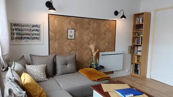En moderne stue med en hjørnesofa, et sofabord, en bogreol og en tapetvæg.