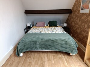 Et soveværelse med en seng, to sengeborde, en lampe og en tapetvæg.