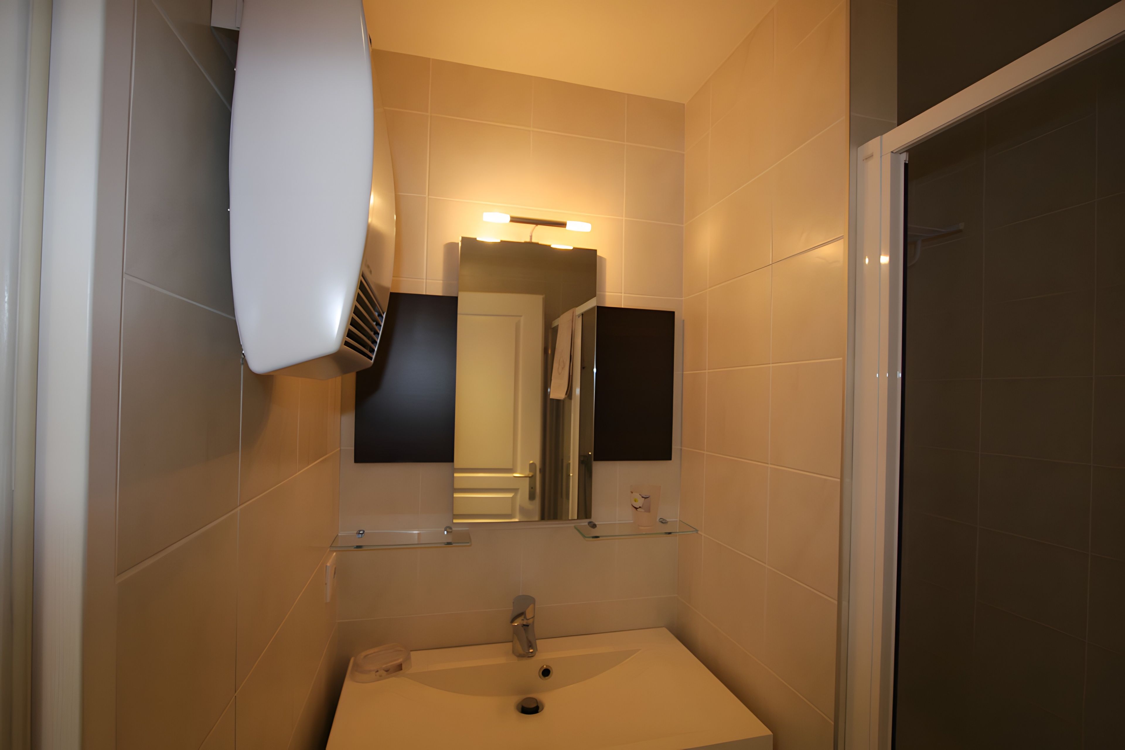 A bathroom with a white sink, a mirror, and a shower area.
