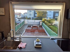 A kitchen with a window view of a residential area, a sink, and a countertop with a bottle and cloth. - Hornagøta 4, 2 (Mid & Attic floor) (Thorshavn)