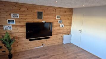 Une pièce avec un mur en bois, un téléviseur à écran plat fixé sur ce mur, et une porte sur le côté droit.