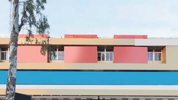 A multi-story building with a flat facade, large windows, and a blue lower section.