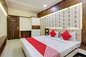 A hotel room with a bed, bedside tables, a wardrobe, and a decorative wall panel. - Hotel O Bada Ganpati Indore Airport (Indore)