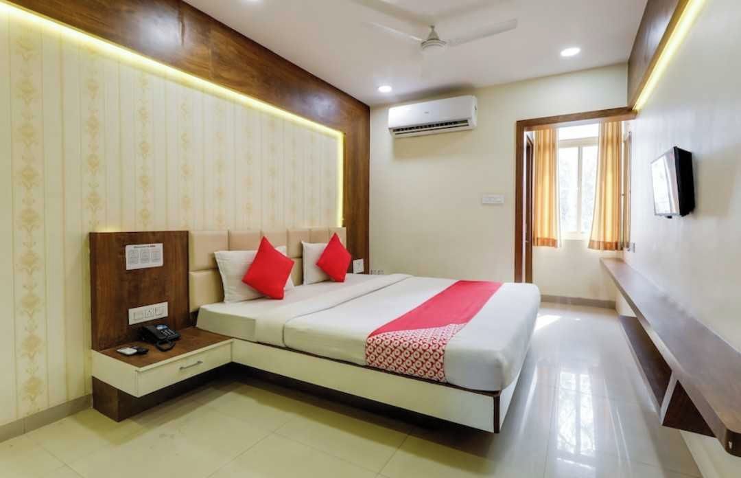 A hotel room with a bed, bedside table, and a wall-mounted TV.