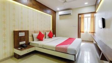 A hotel room with a bed, bedside table, and a wall-mounted TV.