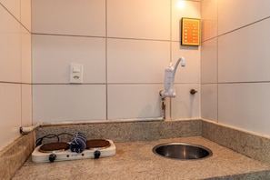 A bathroom with a sink, a faucet, a wall-mounted light, and a small heater. - Copacabana Must Praia e Conforto (Rio de Janeiro)