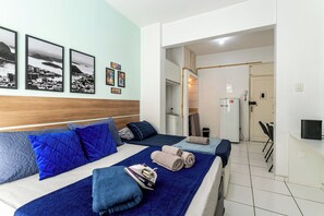 Ett hotellrum med två sängar, en sänggavel i trä och en vägg med inramade tavlor.