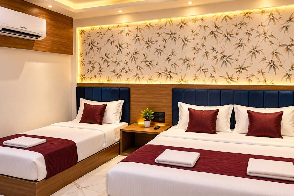 A hotel room with two beds, a wall-mounted air conditioner, and a patterned wall.