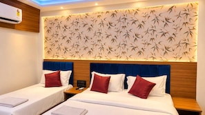 A hotel room with two beds, a wall with a bamboo leaf pattern, and an air conditioning unit. - Collection O Bandra Terminus (Mumbai)