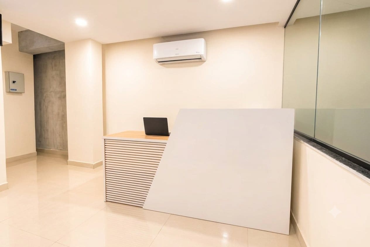 A reception area with a reception desk, a wall-mounted air conditioner, and a glass partition.