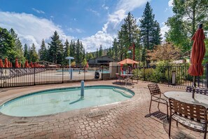 A pool area with a brick patio, metal fencing, and outdoor seating. - New! Ski-in/ski-out! Condo in Northstar Resort (Truckee)