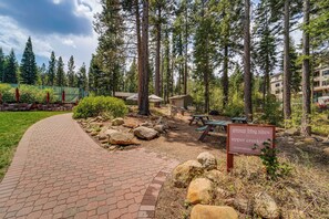 A paved walkway leading to a picnic area with benches and a sign indicating group BBQ sites. - New! Ski-in/ski-out! Condo in Northstar Resort (Truckee)