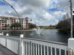Vista al agua con barandilla de puente, una fuente y un edificio de varios pisos con balcones.