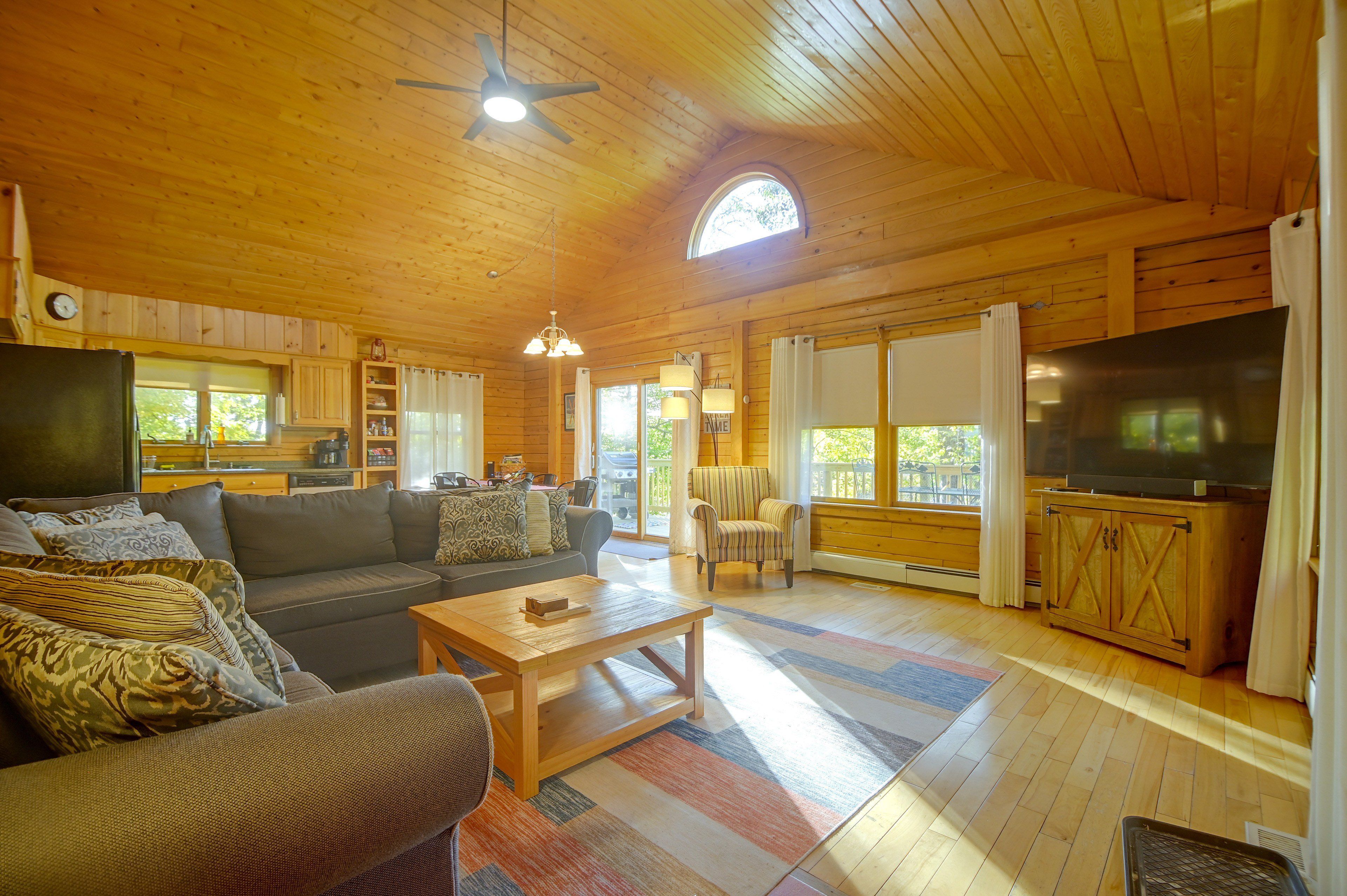 Un salón amplio con techo de madera, un sofá grande, una mesa de centro y un televisor.