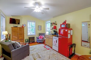 Cocina compacta con un refrigerador rojo, un microondas y una estufa. Cuenta con una zona de comedor con una silla y una mesa.