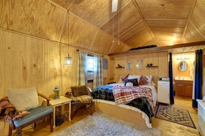 Ein gemütlicher Holzraum mit einem Bett, einem Sessel, einem kleinen Tisch und einem Spiegel.