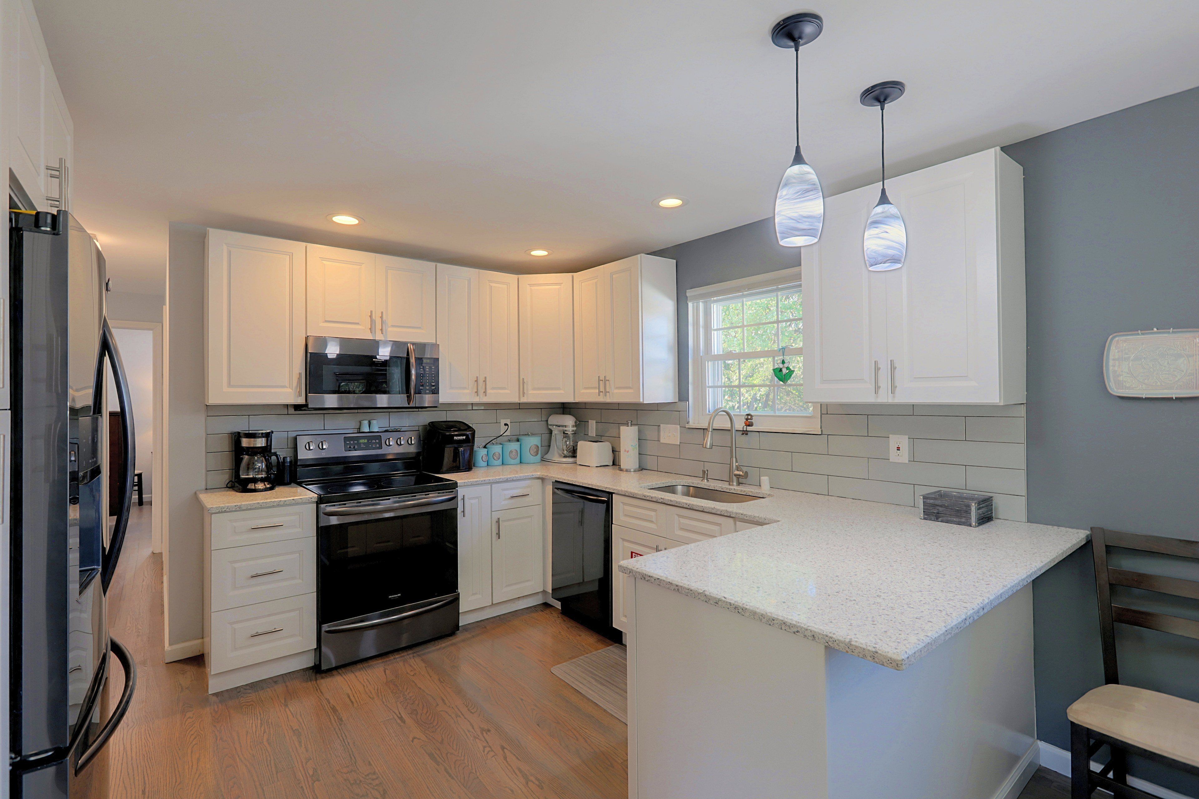 A modern kitchen with white cabinetry, stainless steel appliances, and a granite countertop.