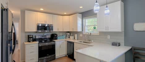A modern kitchen with white cabinetry, stainless steel appliances, and a granite countertop.