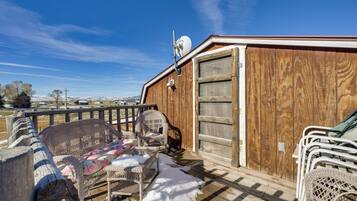 A wooden deck with wicker furniture and a snow-covered ground.