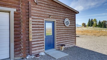 A rustic log cabin with a blue door, a welcome sign, and a logo indicating it was established in 2014.