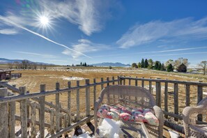 A wooden fence with a wicker chair and cushions, a clear sky, and a snowy landscape with distant mountains. - Mountain Views! Peaceful Dillon Cabin w/ Yard (Dillon)