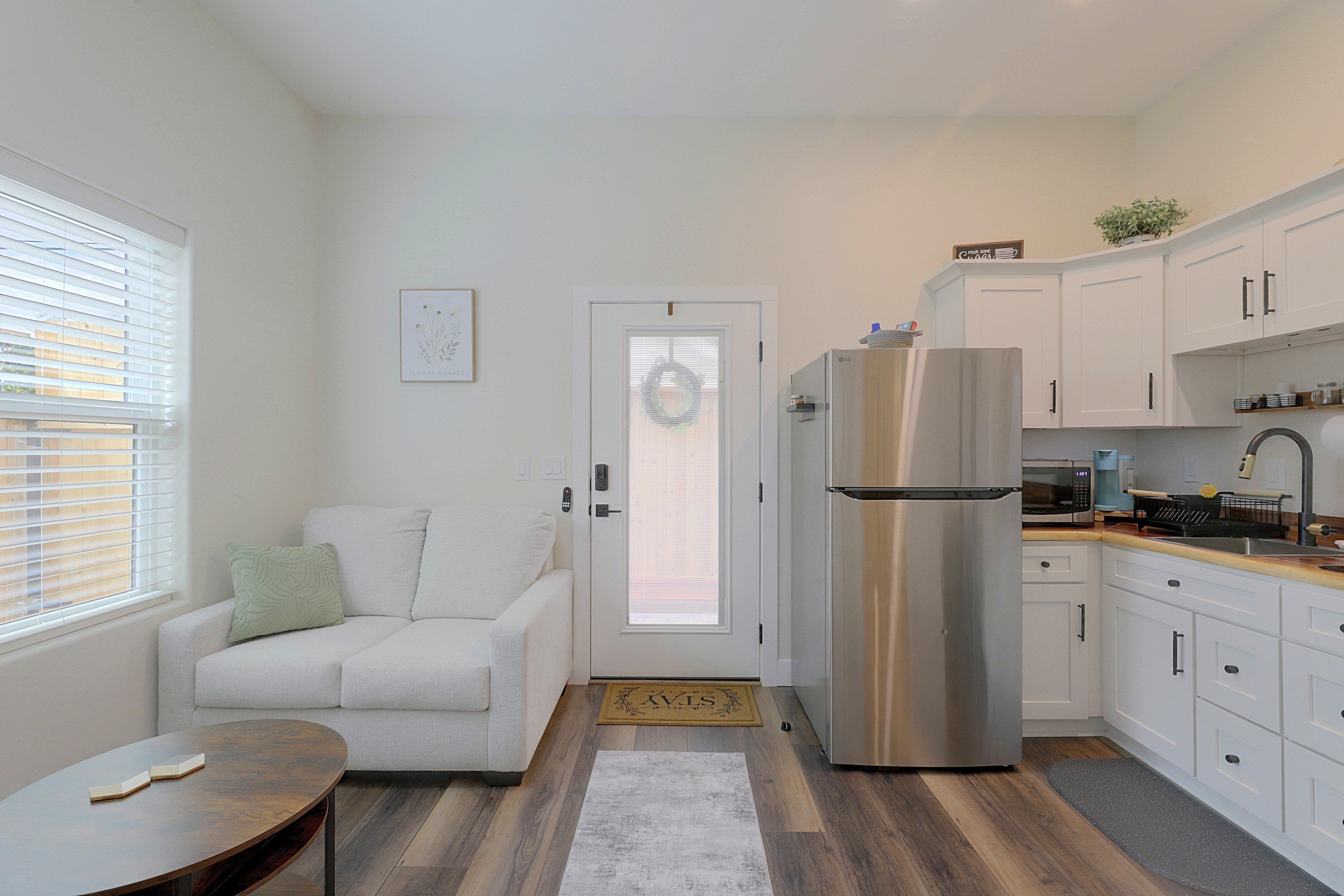 A compact living space with a kitchenette, a sofa, a dining table, and a refrigerator.