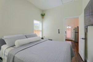 Un dormitorio con cama, ventana con persianas, puerta y refrigerador.