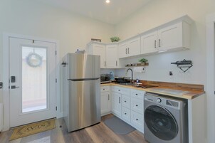 Cocina compacta con armarios blancos, refrigerador de acero inoxidable, lavadora integrada y una pequeña encimera.