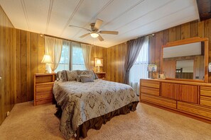 Un dormitorio con cama, mesitas de noche, cómoda y ventilador de techo, además de un espejo grande.