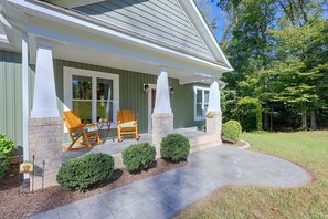 A house with a porch, two rocking chairs, and a welcome sign.