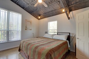 Un dormitorio con una cama, ventilador de techo, ventana y puerta.