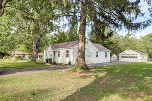 A single-story house with a front porch, a garage, and a large tree in front.