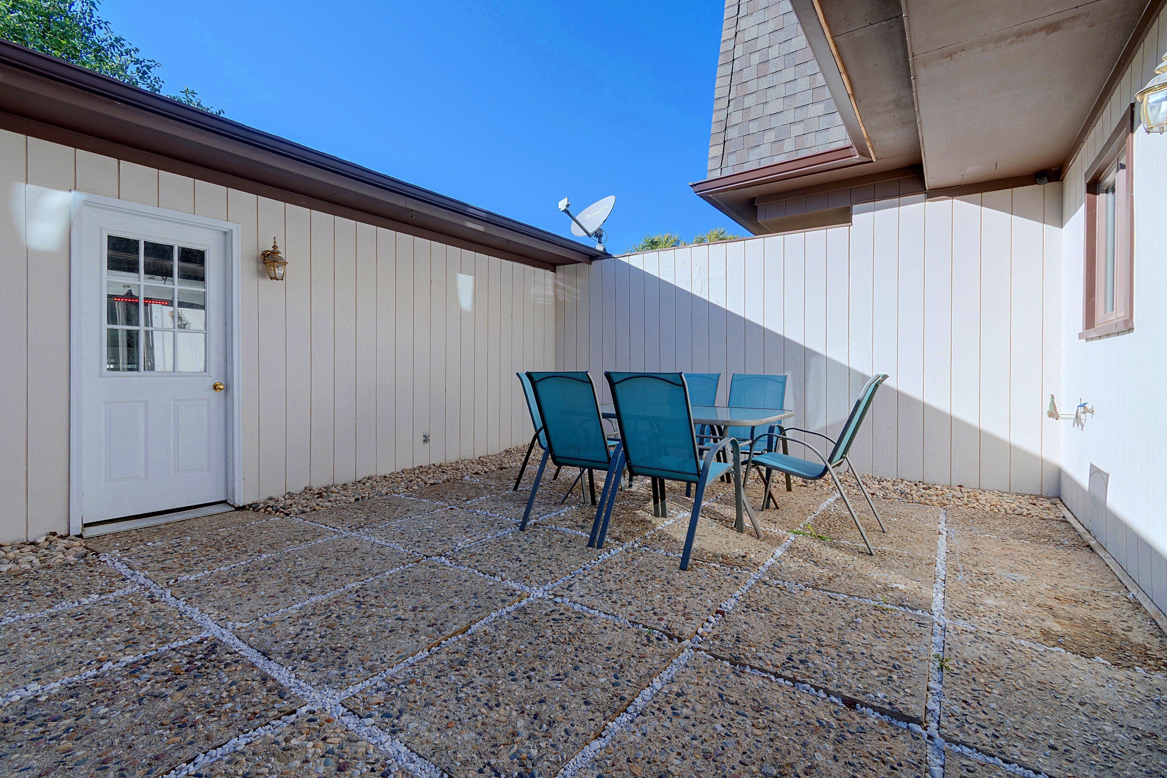 A patio with a table and chairs, a door, and a satellite dish.