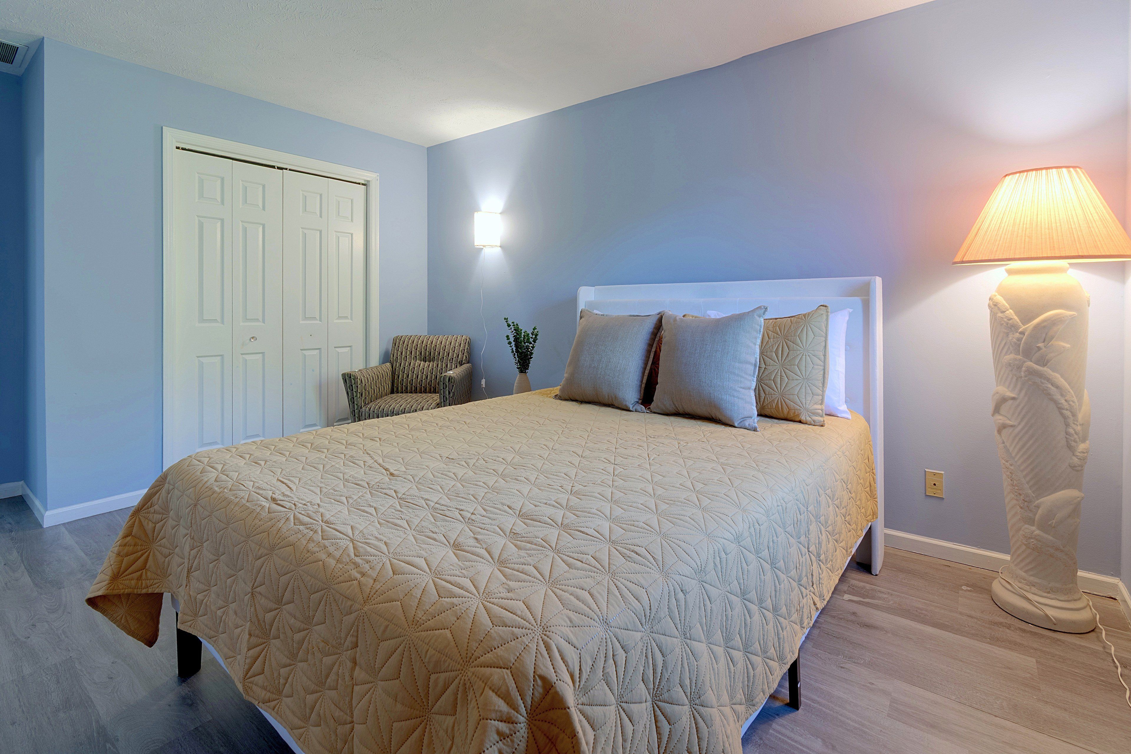Une chambre à coucher avec un grand lit, une chaise, une lampe et une porte.
