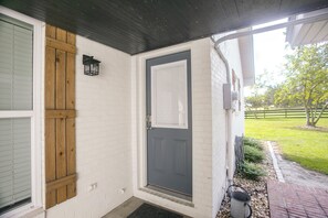 A house entrance with a dark door, white brick walls, and a wooden door frame.