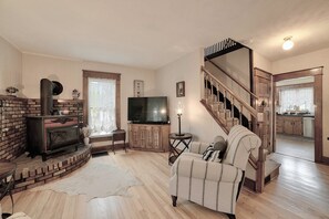A living room with a fireplace, television, sofa, and a staircase leading to another room.