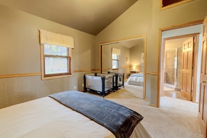 A bedroom with a bed, a window, a mirror, and a door leading to a bathroom.