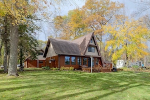 A cabin with a sloped roof, large windows, and a deck.