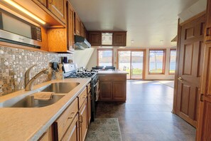 A spacious kitchen with wooden cabinets, a stainless steel sink, and a large island with a stove.