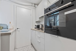 Cocina compacta con horno integrado, lavamanos y ventana.