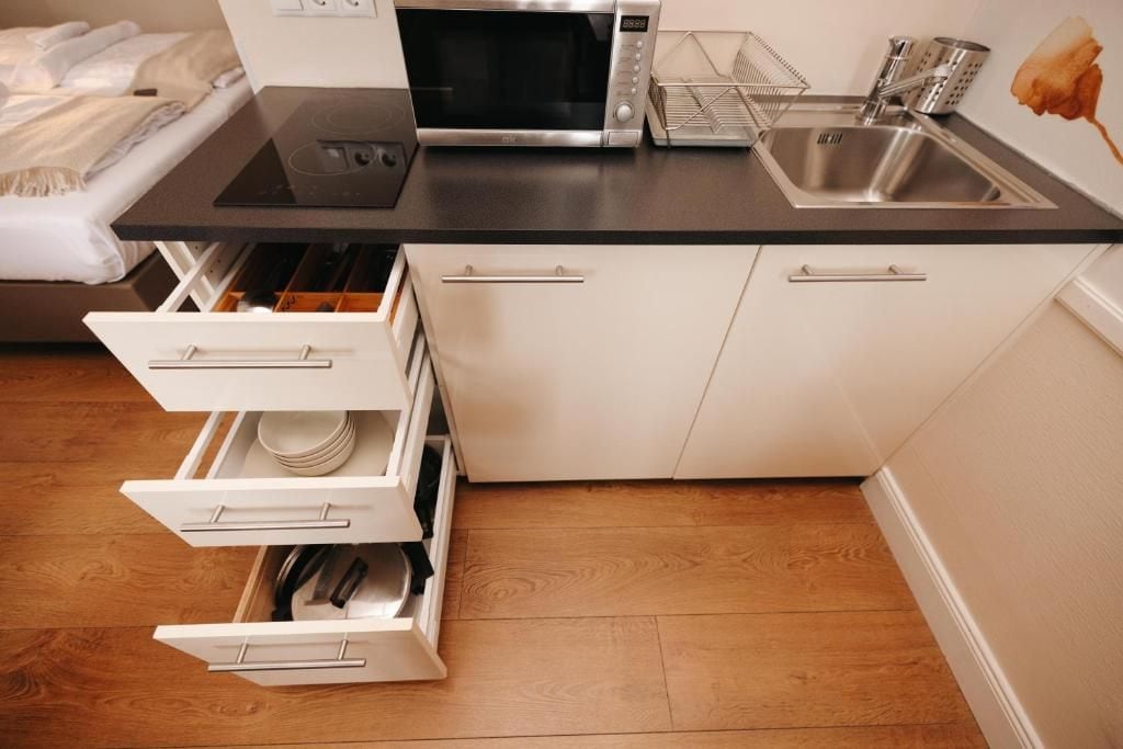 A kitchen with a microwave, sink, and white cabinets.