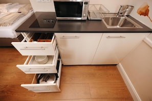 A kitchen with a microwave, sink, and white cabinets. - Apartments Universitaet by ALPAMI (Wien)
