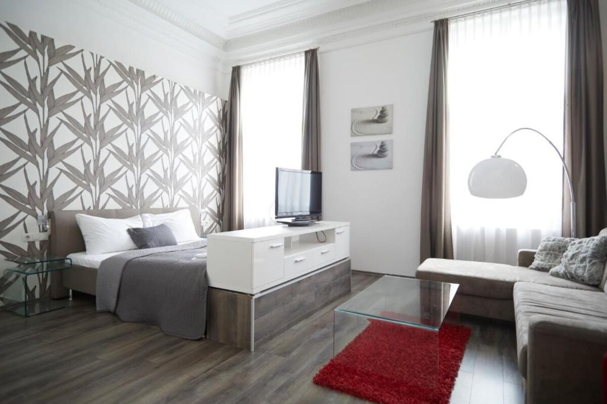 A modern living room with a bed, sofa, and a glass coffee table.