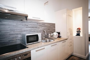 A modern kitchen with a microwave, sink, and stainless steel range hood. - Apartments Universitaet by ALPAMI (Wien)