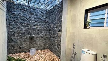 A bathroom with a stone wall, a skylight, a toilet, and a potted plant.