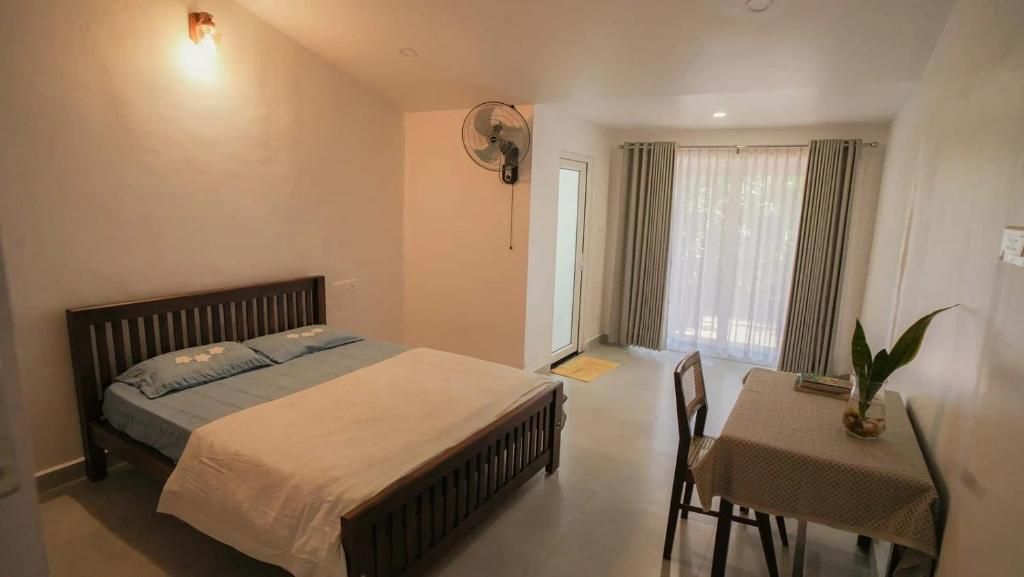 A bedroom with a bed, bedside table, and a fan.