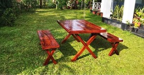 A wooden picnic table with benches in a grassy outdoor area. - Thondiyar Estate Bungalow By LexStays (Vandiperiyar)