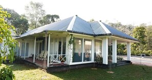 A house with a covered porch, large windows, and a sloped roof. - Thondiyar Estate Bungalow By LexStays (Vandiperiyar)