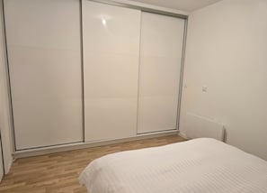 Ein Schlafzimmer mit einem Bett, Holzboden und einem weißen Kleiderschrank.